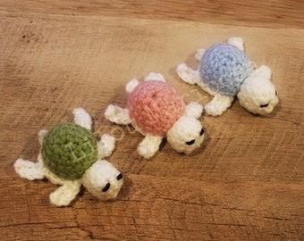 May include: Three crocheted turtle toys. One is green, one is pink, and one is blue.