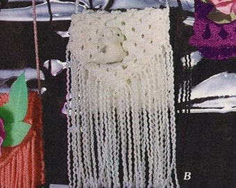 Puede incluir: Bolso blanco de crochet con un dije de pájaro blanco y flecos. El bolso está colgado de un cordón blanco.