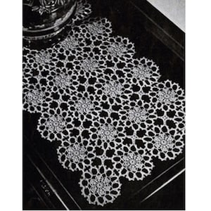 May include: White crocheted table runner with a delicate floral pattern. The runner is made with a fine thread and has a scalloped edge.