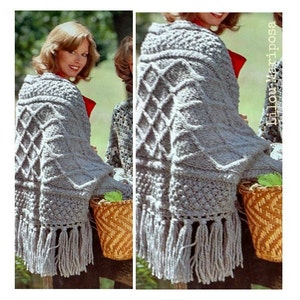 May include: A grey knitted shawl with a diamond pattern and fringe. The shawl is draped over a woman's shoulders.
