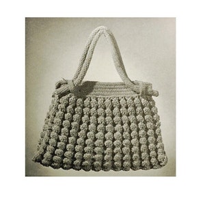 Op de afbeelding: Een gehaakte handtas met een textuur, een bolletjes design. De tas heeft twee handvatten en een geknoopt detail aan elke kant.