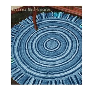May include: A blue and white crocheted round rug with a fringe border. The rug has a concentric circle pattern.