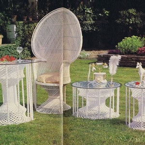 以下が含まれることがあります： 孔雀の椅子、丸いテーブル2台、ガラス天板が付いた白い籐製の屋外用家具セット。テーブルはロープのようなベースでユニークなデザインです。