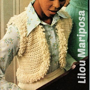 Puede incluir: Un chaleco blanco de ganchillo con borde de flecos. El chaleco se lleva sobre una camisa azul claro con estampado floral. El texto "Lilou Mariposa" es visible en la imagen.