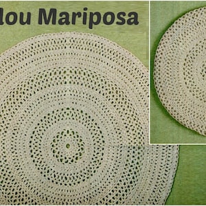 May include: A close-up of a beige crocheted round rug with a circular pattern. The rug is on a green surface.