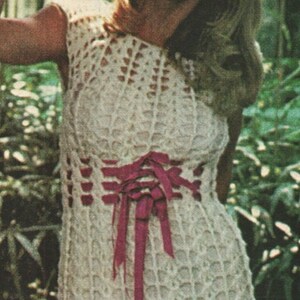May include: A white crocheted sleeveless dress with a pink ribbon tie at the waist.