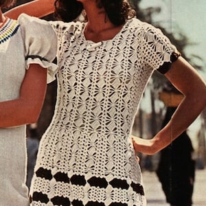 May include: A white crochet dress with a brown and white striped bottom. The dress has a round neckline and short sleeves.