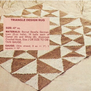 May include: A square, handmade rug with a triangle design. The rug is made of brown and white yarn, with each triangle section alternating in color. The text "TRIANGLE DESIGN RUG" is visible in the image. The rug measures 40 inches square.