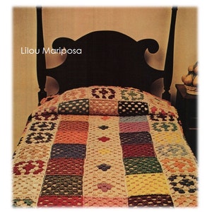 Puede incluir: Una colcha de ganchillo multicolor con un patrón cuadrado. La colcha está sobre una cama con una cabecera negra. El texto "Lilou Mariposa" es visible en la imagen.