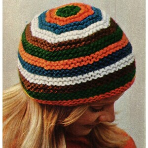 May include: A colorful striped knit hat with green, orange, blue, white, and brown stripes. The hat is made with a chunky yarn and has a simple, classic design.