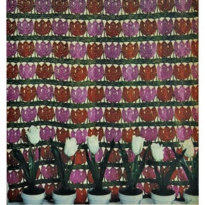 May include: A crocheted wall hanging with a repeating pattern of pink and red tulips. The wall hanging is decorated with five white tulips in pots.