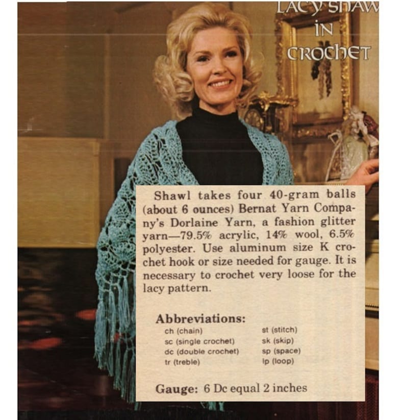 May include: A woman wearing a blue crocheted shawl. The text in the image reads "Lacy Shaw in Crochet" and includes instructions for making the shawl using Bernat Yarn Company's Dorlaine Yarn. The instructions include the yarn composition, hook size, gauge, and abbreviations for crochet stitches.