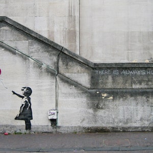 May include: A black and white stencil of a girl letting go of a red heart-shaped balloon on a gray concrete wall. The text "There is always hope" is written in white chalk on the wall.