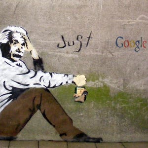 Peut inclure: Un pochoir noir et blanc d'Albert Einstein sur un mur de béton gris. Il est assis, la tête dans la main, et tient une bouteille verte. Le texte "Just Google it" est écrit en lettres noires et colorées sur le mur.