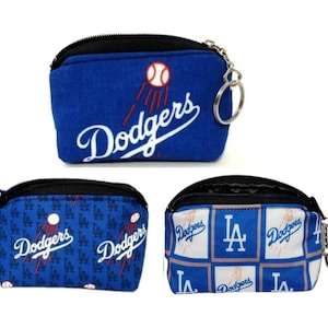 May include: Three blue and black zippered coin purses with the Los Angeles Dodgers logo. The first purse has a large "Dodgers" logo with a baseball. The second purse has a smaller "Dodgers" logo with a baseball and the letters "LA" repeated. The third purse has a checkered pattern with the words "Dodgers" and "LA" repeated.