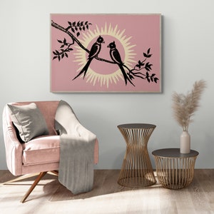 K&ouml;nnte beinhalten: Ein rosa-wei&szlig;er Druck von zwei schwarzen V&ouml;geln, die auf einem Ast sitzen, mit einer Sonne dahinter. Der Druck ist gerahmt und h&auml;ngt an einer Wand.