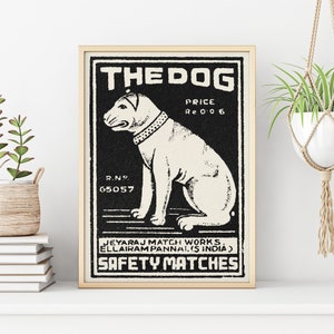 May include: Black and white vintage matchbox label with a cartoon dog illustration. The label reads "THE DOG", "PRICE Re 0 0 6", "R.N. 65057", "JEYARAJ MATCH WORKS ELLAIRAM PANNAL (S INDIA)", and "SAFETY MATCHES".