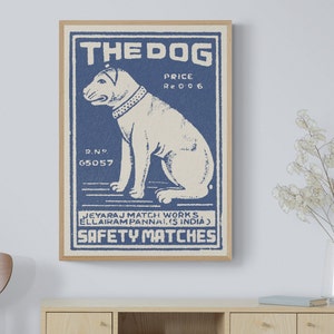 May include: Vintage blue and white matchbox label with a cartoon dog illustration. The label reads "The Dog" and "Safety Matches".