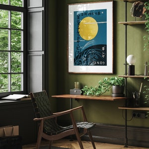 May include: A framed poster with a Japanese design featuring a large yellow moon, green grass, and the text "金色の夢を乗せて" in Japanese. The poster is hanging on a green wall in a room with a wooden desk, a chair, and a potted plant.