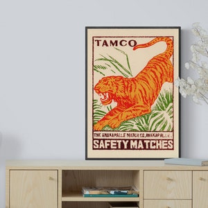 May include: Vintage matchbox label featuring a bright orange tiger leaping through green foliage. The label reads "TAMCO" and "THE ANAKAPALLE MATCH CO. ANAKAPALLE. SAFETY MATCHES".