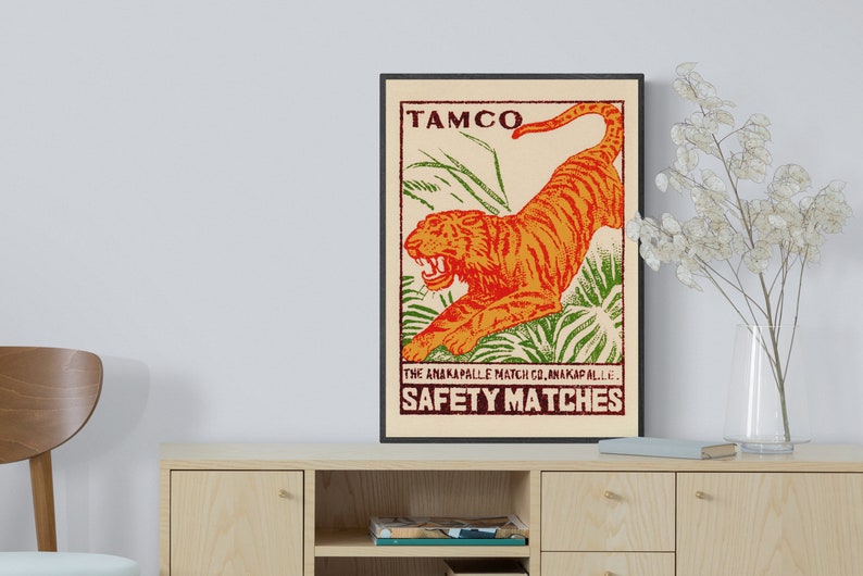 May include: Vintage matchbox label featuring a bright orange tiger leaping through green foliage. The label reads "TAMCO" and "THE ANAKAPALLE MATCH CO. ANAKAPALLE. SAFETY MATCHES".