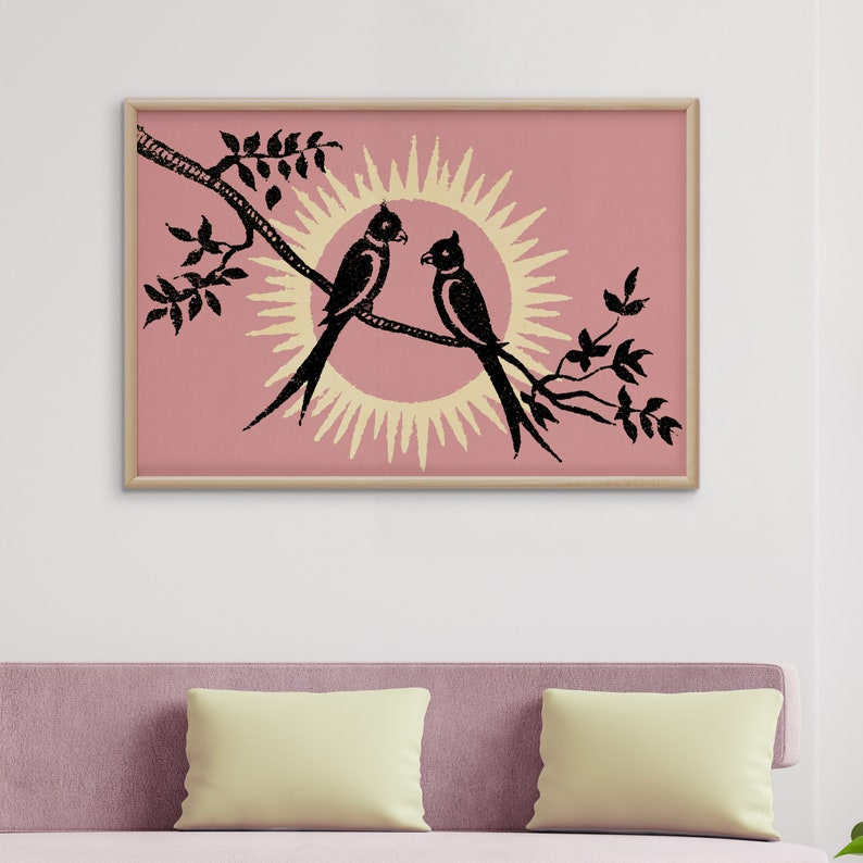 K&ouml;nnte beinhalten: Ein gerahmter Druck mit rosa Hintergrund, auf dem zwei schwarze V&ouml;gel auf einem Ast sitzen, hinter dem sich eine gelbe Sonne befindet.