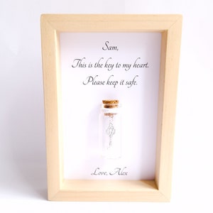 Small frame with a personalised quote containing a miniature glass bottle centrepiece by under the blossom tree