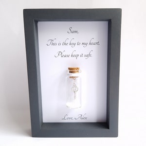 handmade personalised frame with a miniature glass bottle by under the blossom tree