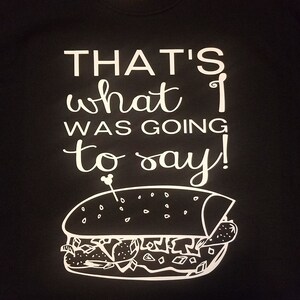 Op de afbeelding: Zwart t-shirt met witte tekst: "THAT'S what I was going to say!". Onder de tekst staat een witte lijntekening van een sandwich. Het t-shirt heeft een Gildan-label.