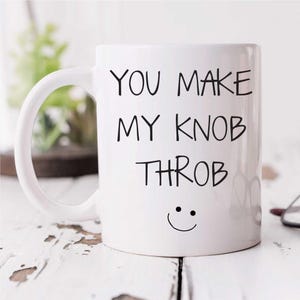 May include: White ceramic coffee mug with a black handwritten message that reads "You make my knob throb" and a smiley face.