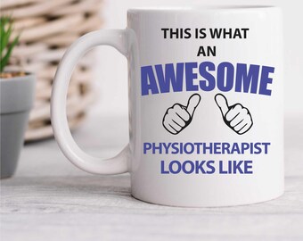 May include: White ceramic mug with a blue and black design. The mug says "This is what an awesome physiotherapist looks like" with two thumbs up.