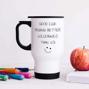 May include: White travel mug with a black handle and lid. The mug has black text that reads "Good luck finding better colleagues than us!" with a smiley face below the text.