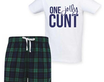 Könnte beinhalten: Ein weißes T-Shirt mit dem Text "ONE jolly CUNT" in Marineblau, kombiniert mit karierten Pyjamahosen in Marineblau und Grün. Die Shorts haben einen weißen Kordelzug.