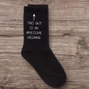 May include: Black socks with white text that reads "This guy is an awesome mechanic".