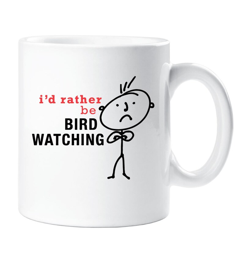 May include: White ceramic coffee mug with a black and white stick figure illustration of a person with a sad face. The text on the mug reads "i'd rather be BIRD WATCHING".