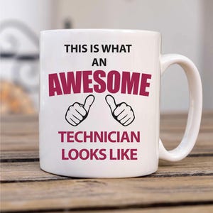 May include: White ceramic coffee mug with a black and burgundy design. The mug reads "This is what an awesome technician looks like" with two thumbs up icons.