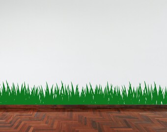 Può includere: Un muro bianco con un adesivo a forma di silhouette di erba verde lungo il bordo inferiore. Il muro è sopra un pavimento in legno marrone scuro.