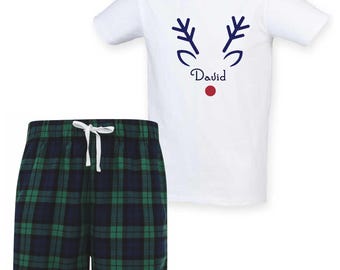May include: White t-shirt with a reindeer face design and the name "David" in script. Paired with green and navy plaid pajama shorts with a white drawstring.