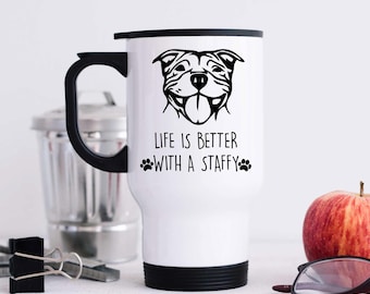 Pode incluir: Caneca de viagem branca com tampa e alça pretas. A caneca tem uma ilustração em preto e branco de um Staffordshire Bull Terrier com o texto "Life is better with a Staffy" e pegadas.
