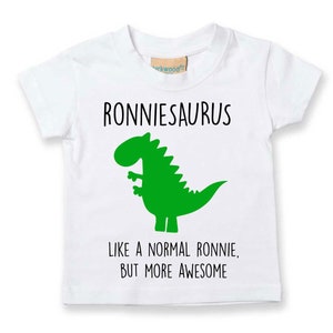 May include: White t-shirt with a green dinosaur graphic and the text "Ronniesaurus Like a normal Ronnie, but more awesome".