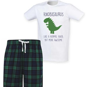 May include: White t-shirt with a green dinosaur graphic and the text "KNOBASAURUS LIKE A NORMAL KNOB, BUT MORE AWESOME." Paired with green and navy plaid pajama shorts with a white drawstring.