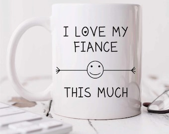 Può includere: Tazza da caffè in ceramica bianca con testo nero che recita "Amo il mio fidanzato così tanto" con un'emoticon sorridente e frecce su entrambi i lati.