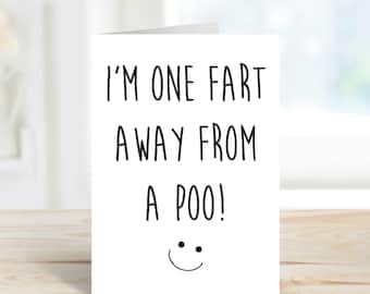 May include: A white greeting card with the text "I'M ONE FART AWAY FROM A POO!" in black, with a smiling face at the bottom. The card is folded and stands upright.