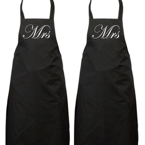 May include: Two black aprons with white cursive text that says "Mrs." on each apron.