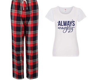 Könnte beinhalten: Ein Pyjama-Set mit rot-schwarz-weiß karierten Pyjamahosen mit Kordelzug und einem weißen T-Shirt. Das T-Shirt hat den Schriftzug "ALWAYS *naughty*" in Marineblau.