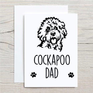 Peut inclure: Une carte blanche avec une illustration en noir et blanc d'un chien Cockapoo. Le texte "Cockapoo Dad" est imprimé en noir sous l'illustration. Deux empreintes de pattes se trouvent de chaque côté du texte.
