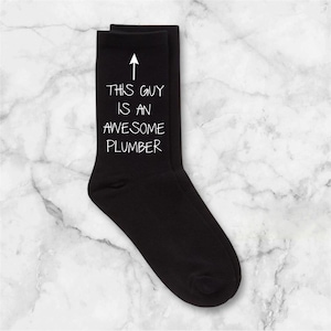 Könnte beinhalten: Schwarze Socken mit einem weißen Pfeil nach oben und dem Text "Dieser Kerl ist ein großartiger Klempner".