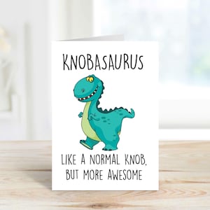 May include: A white greeting card featuring the word "KNOBASAURUS" above a teal cartoon dinosaur with a green belly. The text below the dinosaur reads "LIKE A NORMAL KNOB, BUT MORE AWESOME."