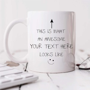 May include: White ceramic mug with a black arrow pointing upwards and the text "THIS IS WHAT AN AWESOME YOUR TEXT HERE LOOKS LIKE" and a smiley face. The mug has a curved handle.