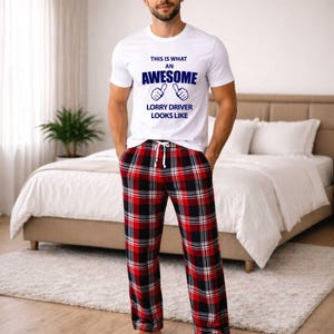 May include: White t-shirt with the text "THIS IS WHAT AN AWESOME LORRY DRIVER LOOKS LIKE" in blue. The person is wearing red, black, and white plaid pajama pants. The pants have a drawstring waist.